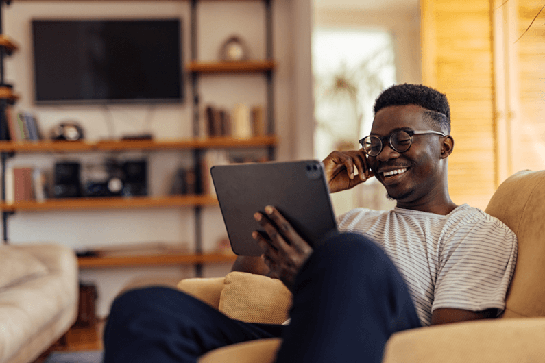 A young man sits and smiles while reviewing financial tips and lessons learned from the kids’ show Sesame Street.