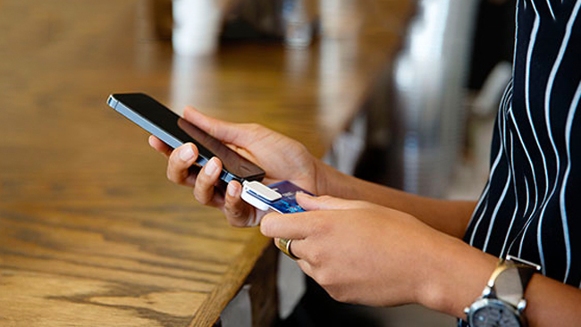 Woman using mobile phone credit card reader