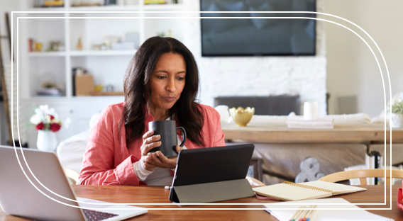 A female business owner holds a cup of coffee and researches strategies for retiring business owners on her laptop.